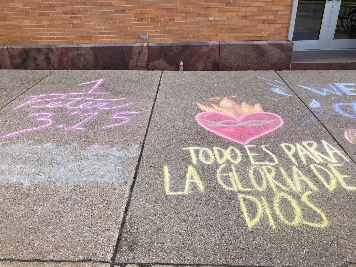 Chalk on the sidewalk reading 1 Peter 3:15 and Todo es para la gloria de Dios